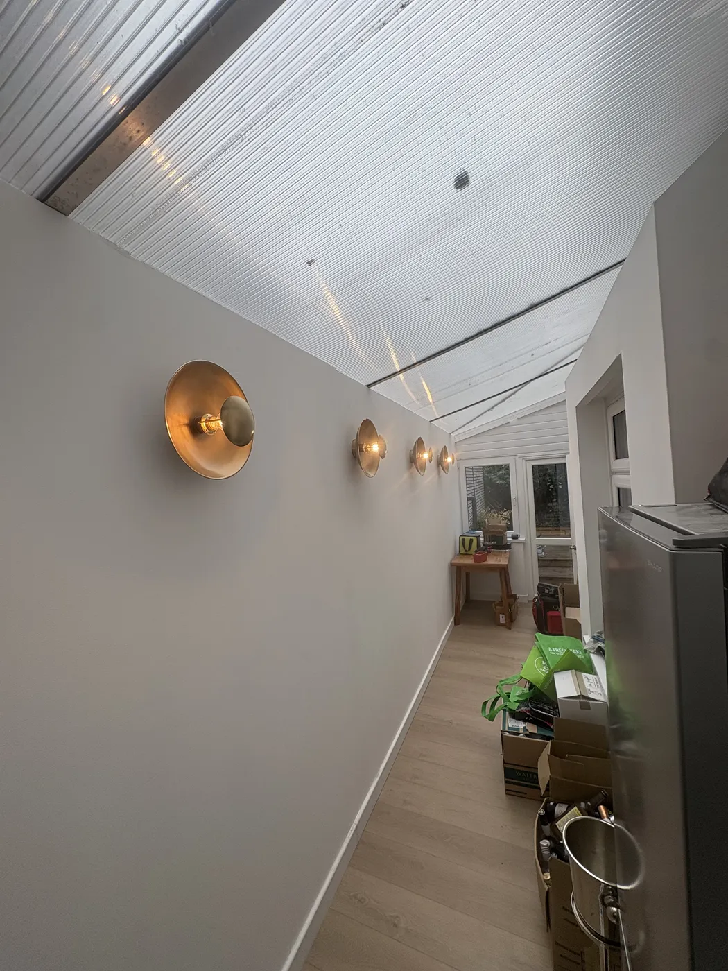 Brass dome wall lights installed along a Barnes side-return under a conservatory roof