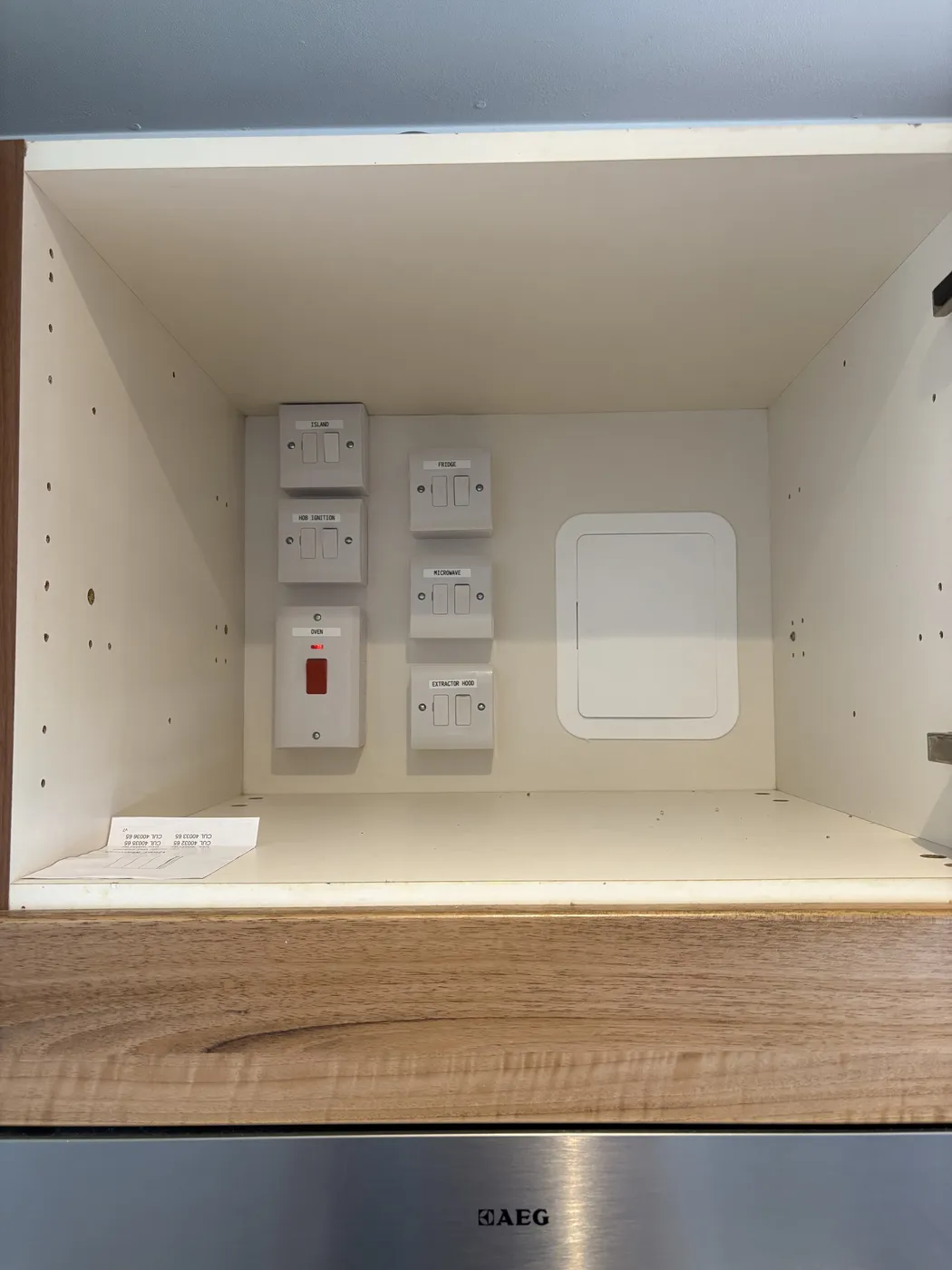 Labelled switched fused spurs and cooker switch installed in a Chiswick kitchen cupboard