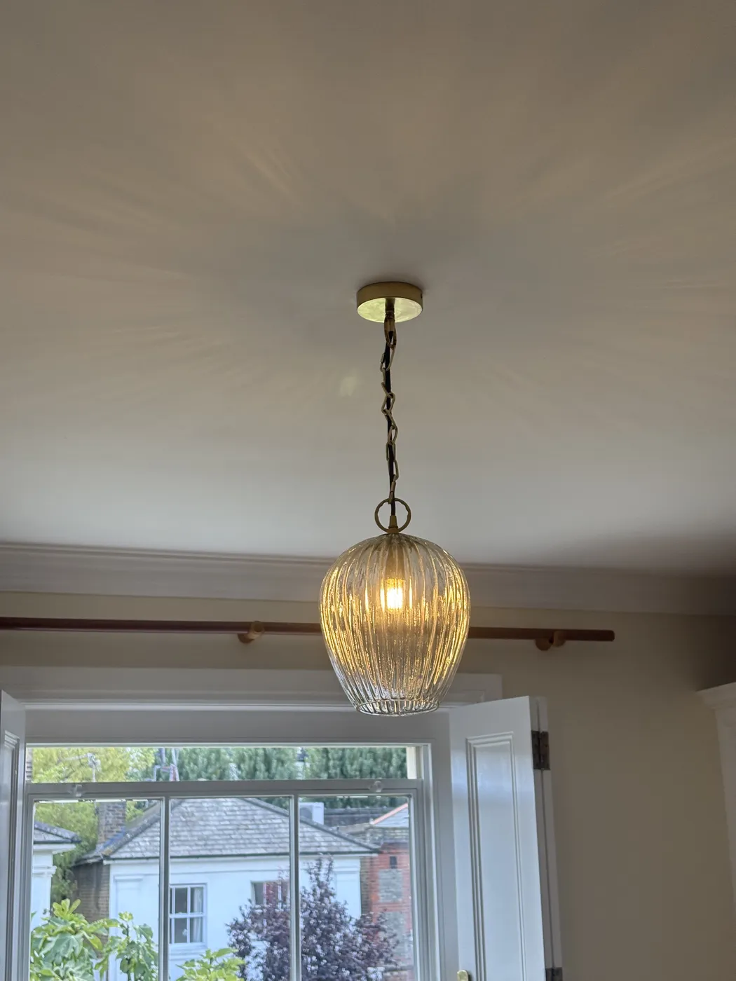 Ribbed glass pendant light on brass chain installed in a Chiswick bedroom