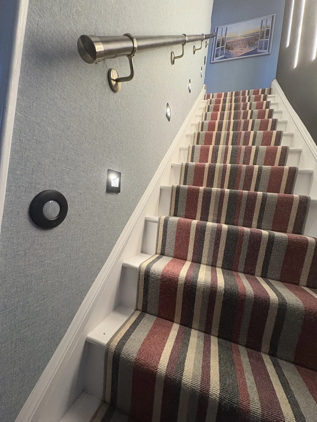 Recessed stair and wall lighting on a Kensington staircase with brass handrail