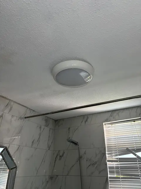 LED bathroom ceiling light installed above a marble-tiled shower in Shepherd's Bush