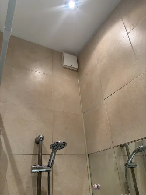 Bathroom extractor fan and downlight installed in a tiled shower area in Acton