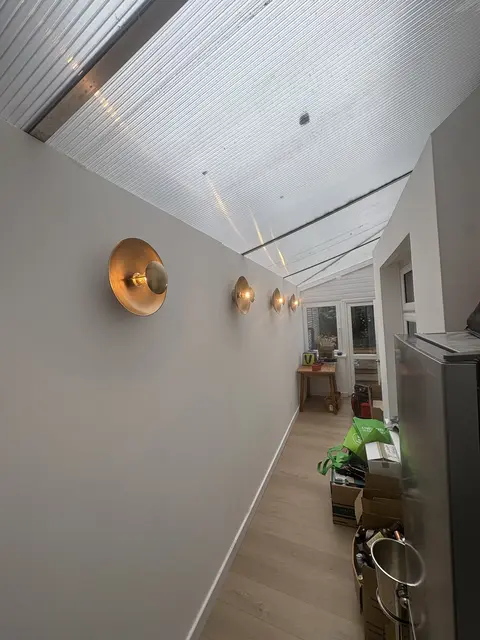 Brass dome wall lights installed along a Barnes side-return under a conservatory roof