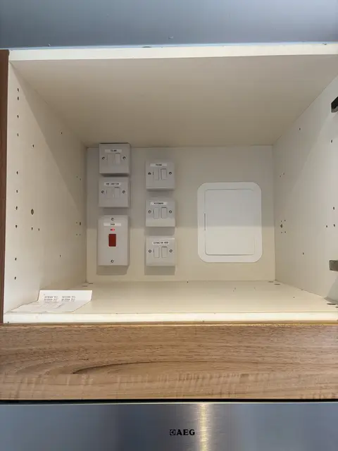 Labelled switched fused spurs and cooker switch installed in a Chiswick kitchen cupboard