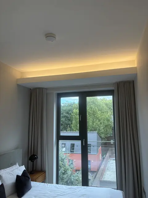 Warm LED cove lighting installed above bedroom curtains in Paddington
