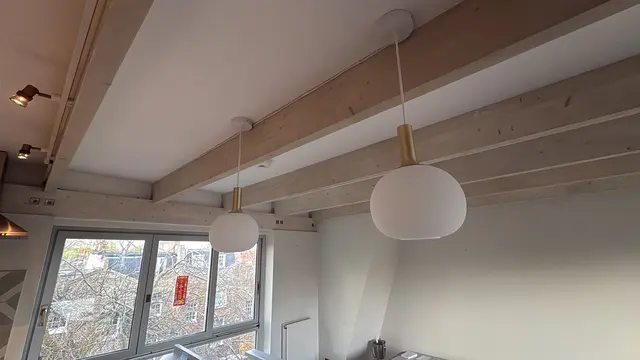 Pair of brass globe pendant lights fitted to a beamed ceiling in Hammersmith